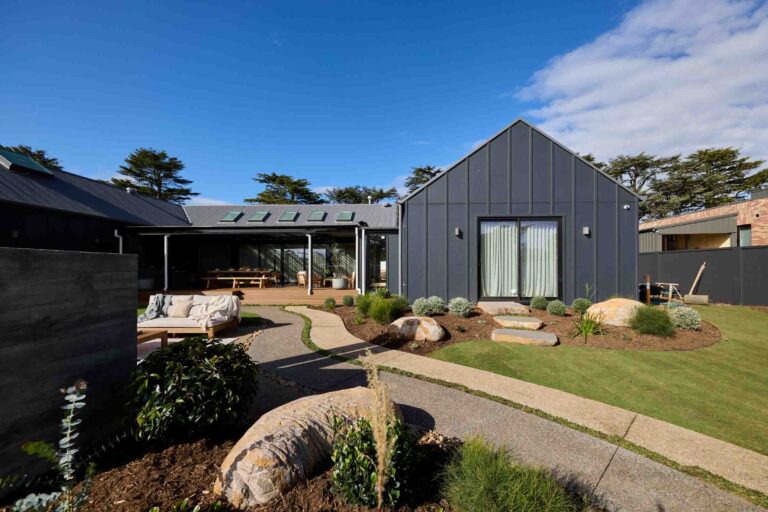 Modern landscape courtyard with basalt stepping stones, outdoor daybed, and steel-clad buildings at Daylesford House 5