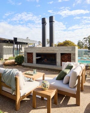 Modern concrete fireplace with timber outdoor furniture and pool backdrop at Daylesford House 5 from The Block
