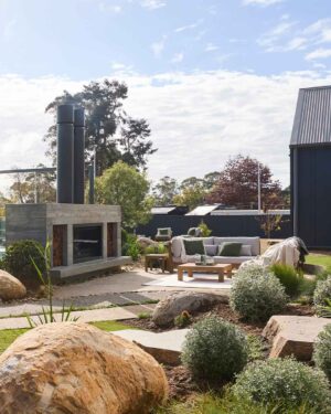 Modern concrete outdoor fireplace with grey lounge seating and natural stone boulders in Daylesford garden