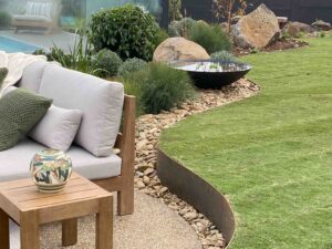 Curved garden beds with native plantings, black water bowl feature and outdoor furniture at Daylesford House 5