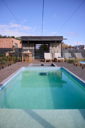 Modern backyard with swimming pool, glass safety fencing, outdoor fireplace and entertaining area in Daylesford