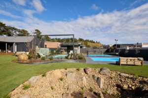 Modern backyard landscape featuring full-size Pickleball court, swimming pool, and mature Bottle Tree at Daylesford house