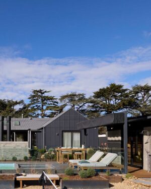 Modern outdoor entertaining area with timber deck, pool, lounge chairs and mature trees at Daylesford House 5