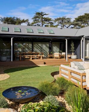 Covered timber deck with dining furniture and circular water feature in foreground at Daylesford House 5 project