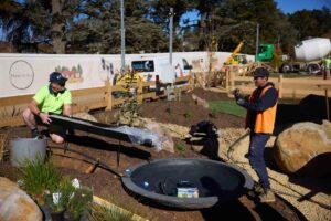 Construction workers installing black circular water feature with bench seating during The Block Daylesford landscape build