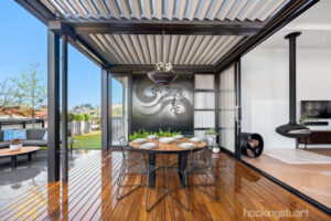 Modern rooftop terrace with blackbutt decking, steel pergola, and outdoor dining area overlooking St Kilda cityscape