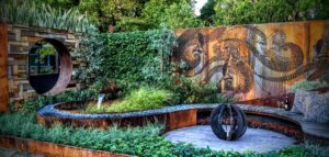Corten steel art screens with wattlebird motifs, curved seating, and central fire feature in award-winning Nagasaki garden