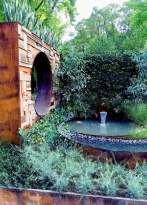 Corten steel water feature with curved spout flowing into circular pool in award-winning Wattlebird Garden, Nagasaki Japan