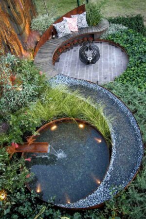 Curved timber bench wrapping around circular paved area with water feature in award-winning Nagasaki garden design