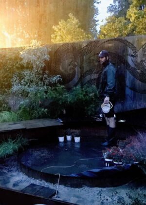 Person tending fire feature at dusk in award-winning Garden of the Little Wattlebird, Nagasaki, Japan