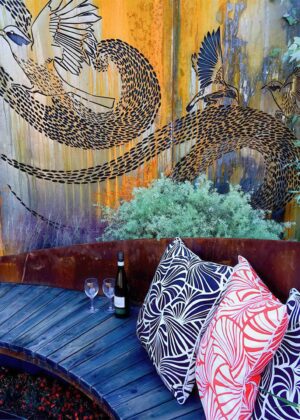 Large-scale wattlebird mural behind curved timber seating with patterned cushions in award-winning Nagasaki garden