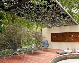 Timber deck with perforated metal pergola creating dappled light in contemporary garden seating area