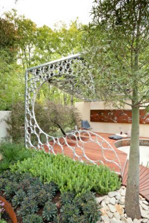 White perforated steel pergola canopy over timber decking with native plantings at The Wave Garden, Carlton Victoria
