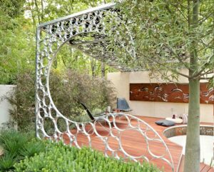 Circular steel garden structure with organic perforations framing pathway in modern landscape design