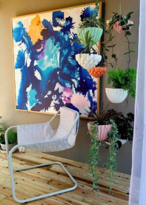 White sculptural hanging planters with trailing plants displayed in modern interior corner with abstract artwork, Nagasaki