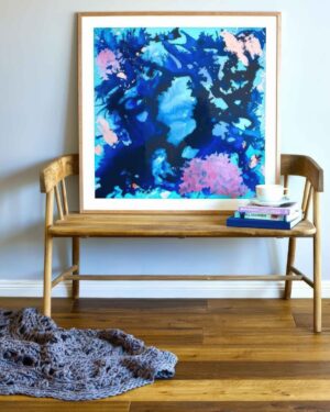 Wooden bench with abstract blue and pink artwork displayed above, styled with books and knitted throw in interior setting