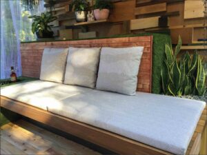 Built-in timber daybed with white cushions on compact balcony garden in Melbourne with vertical timber screening