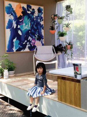 Child sitting in modern interior with vertical hanging planters and abstract blue artwork, Nagasaki Balcony Garden 2015