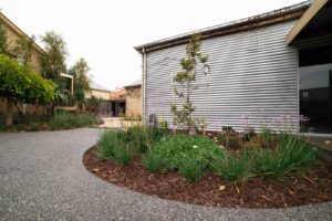 Curved corten steel seating with integrated fire pit and permeable gravel driveway in Ballarat backyard garden