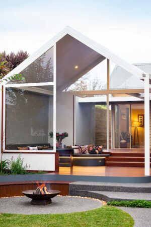 Modern outdoor fire pit with curved corten steel seating and timber decking in Ballarat backyard at dusk