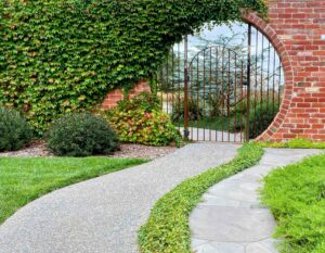 Curved brick archway with climbing ivy and metal gate opening to garden path at Mount Buninyong country estate