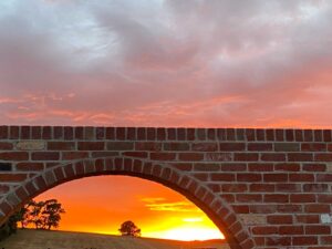 Brick archway framing golden sunset with silhouetted trees at Mount Buninyong country estate garden