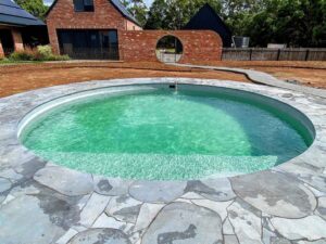 Circular swimming pool with green mosaic tiles and natural stone coping at Mount Buninyong country garden