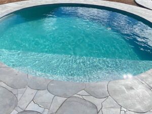 Circular swimming pool with clear turquoise water surrounded by natural stone paving in Mount Buninyong country garden