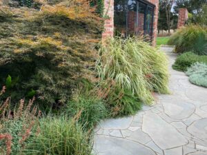 Curved natural stone pathway winds through native grasses and plantings at Mount Buninyong country estate garden