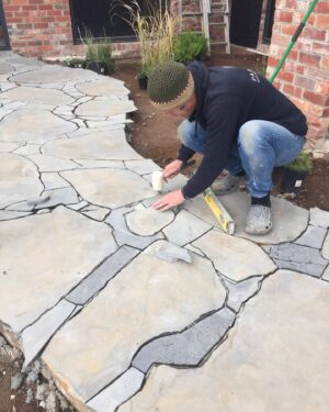 Landscaper installing irregular flagstone pavers with level tool at Mount Buninyong country estate garden project