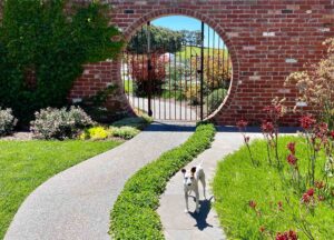 Circular brick moon gate with iron gates leading to native garden landscape in Mount Buninyong country estate