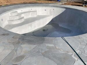 Large circular swimming pool being filled with water, curved stone steps and decorative concrete decking at Mount Buninyong