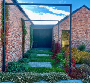 Steel frame arbour entrance with Virginia creeper vines leading to dark timber door at Mount Buninyong country estate