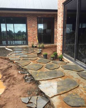 Natural stone paving being laid around brick house with large windows at Mount Buninyong country estate project