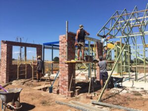 Construction workers building timber roof frame and brick walls at Mount Buninyong country estate construction site