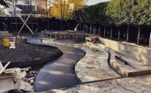 Curved exposed aggregate concrete paths under construction with timber formwork and construction equipment visible