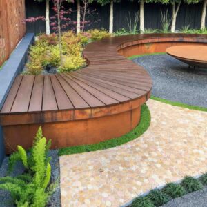 Curved timber deck with corten steel retaining wall, surrounded by native grasses and ferns in contemporary garden setting
